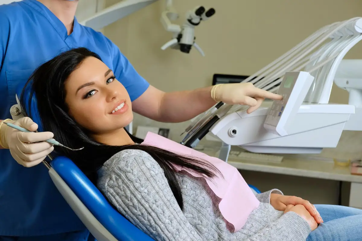 A close-up of a smiling woman showing bright restored teeth, with dental tools and tooth models in the background representing modern restorative dentistry treatments.