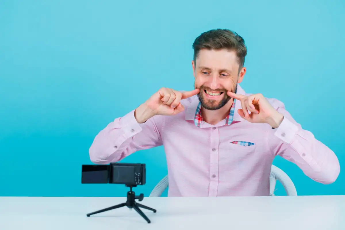 Close-up of an influencer smiling away loudly in front of a camera.